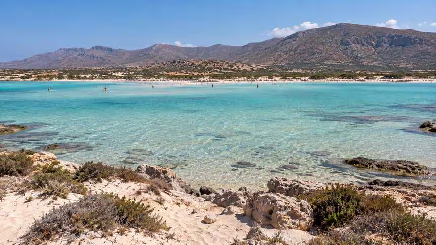elafonissi__near Elafonissi Beach in Crete, with crystal-clear turquoise water, sandy shores and rugged mountains rising along the coastline.