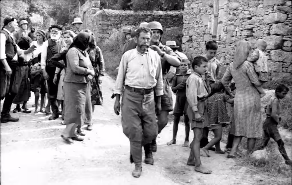 germans_crete 01 A historical black-and-white photograph showing German soldiers and Cretan civilians during World War II in Crete.