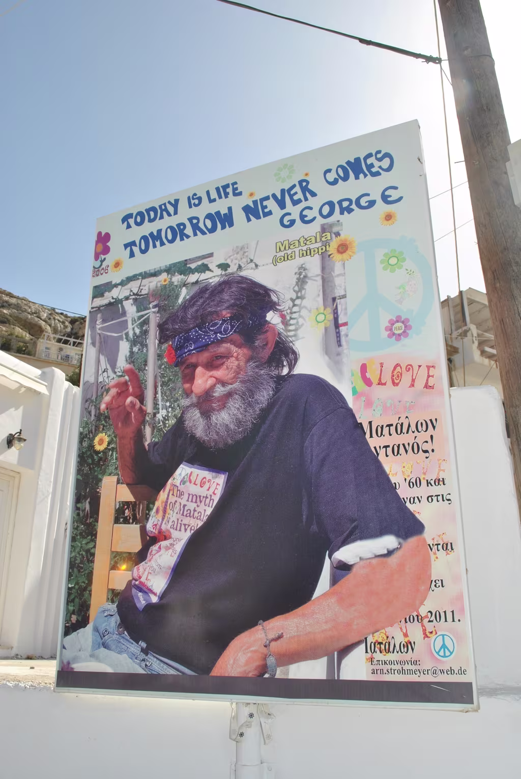 mermaid_cafe_matala A commemorative poster in Matala, Crete, featuring a bearded local figure and the slogan “Today is life, tomorrow never comes,” celebrating Matala’s hippie heritage.