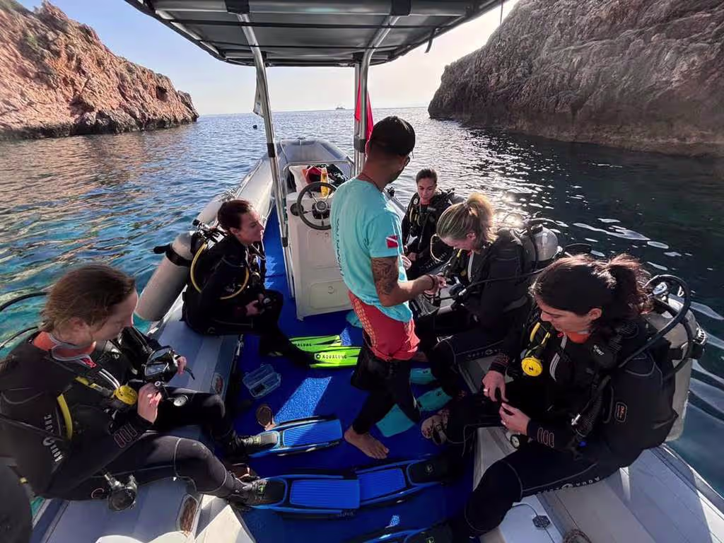 technical_dive_crete A group of scuba divers preparing for a technical dive aboard a boat in a rocky coastal cove near Crete.